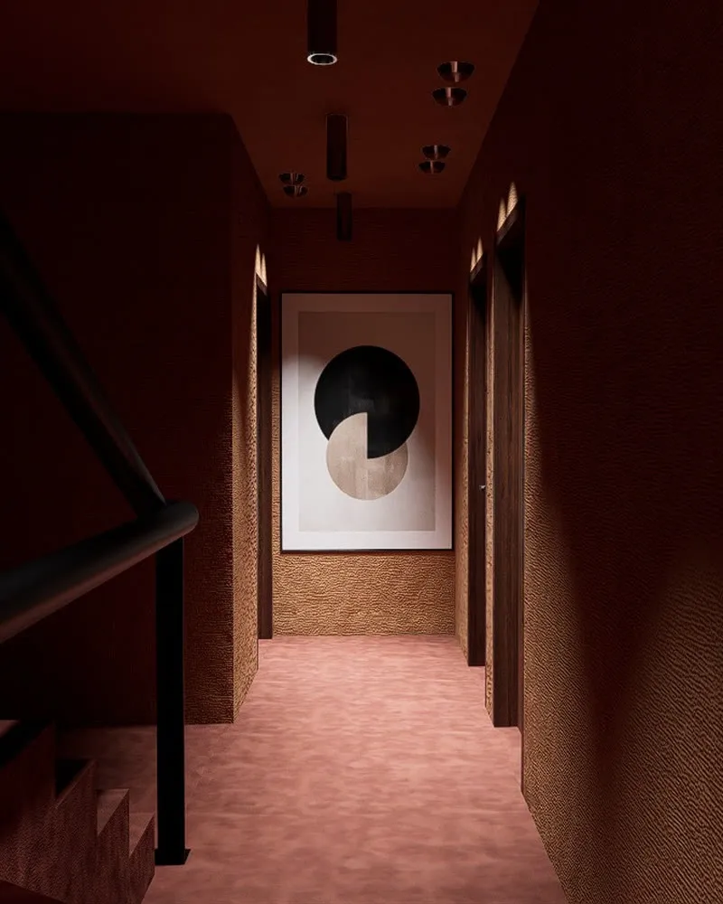 Un couloir de l'hôtel aux murs bordeaux, avec un tableau au fond.