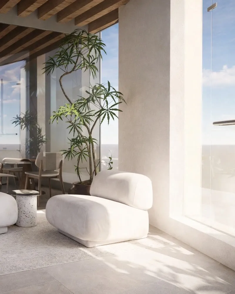 Le salon d'accueil de l'hôtel : deux fauteuils blancs devant une baie vitrée.