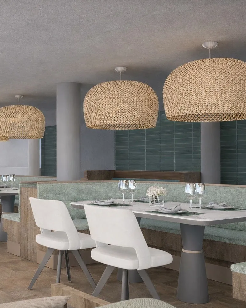 La mezzanine du restaurant : suspensions en osier, banquettes vert sauge et tables blanches.